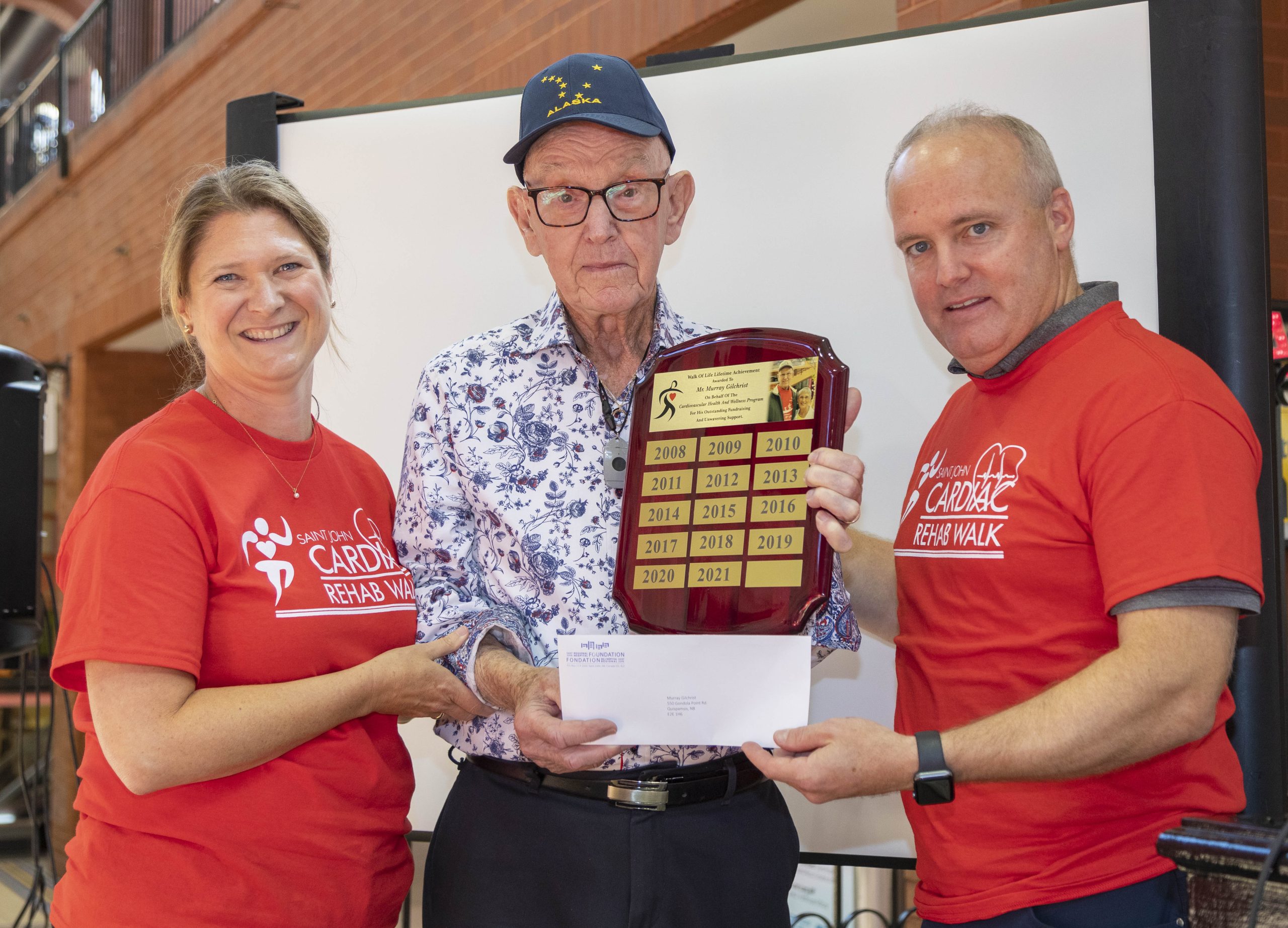 Billie Jo Mabey, Nurse Manager, Cardiac and Pulmonary Rehabilitation, SJRH (left) and Jamie Gallagher, President and CEO of Saint John Regional Hospital Foundation (right) present Murray Gilchrist with a lifetime achievement award for his 15+ years of volunteering and fundraising for the Cardiac Rehab Program.
